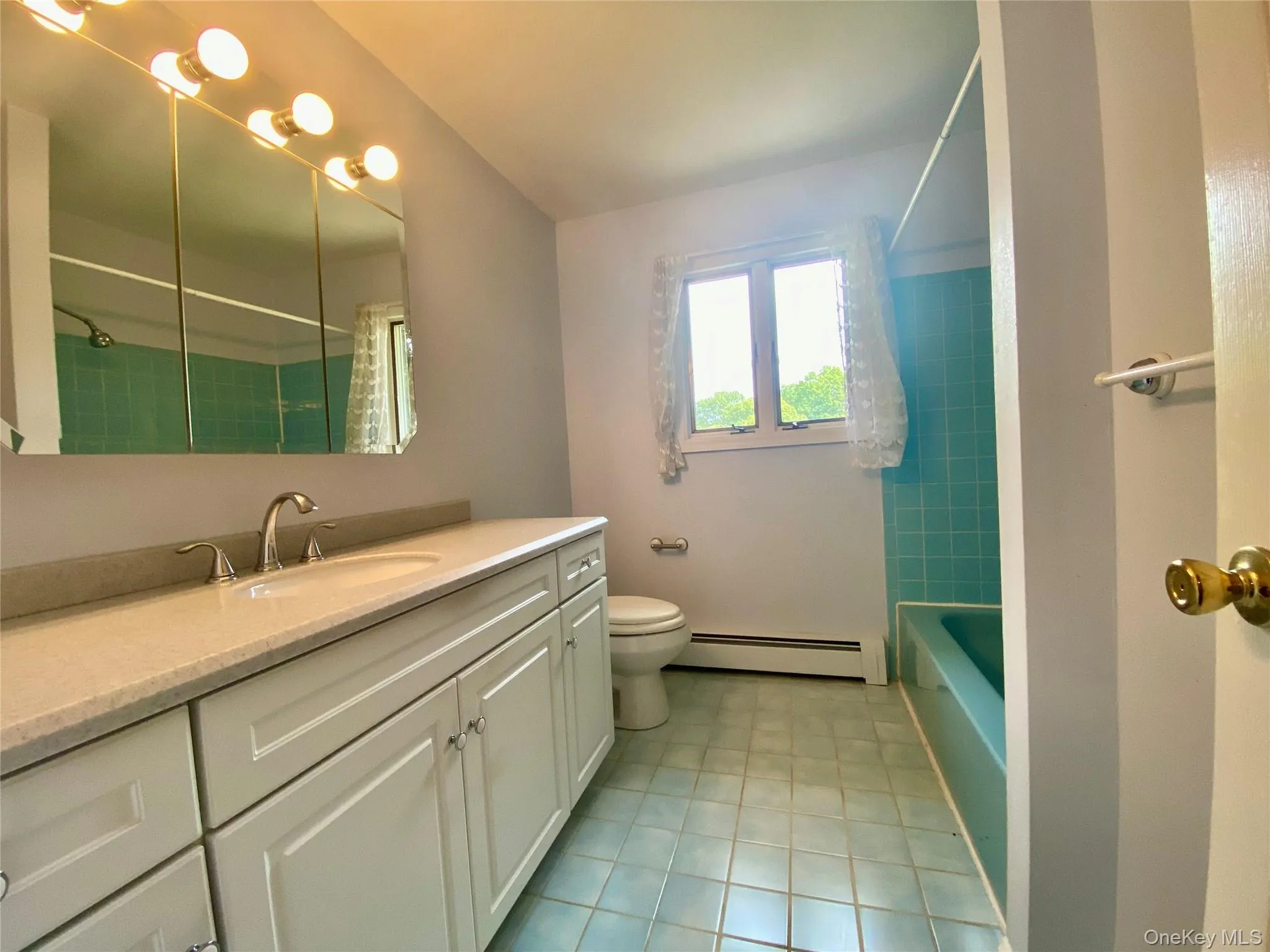 Bathroom featuring vanity, a baseboard radiator, and shower / bath combination Bathroom featuring vanity, a baseboard radiator, and shower / bath combination