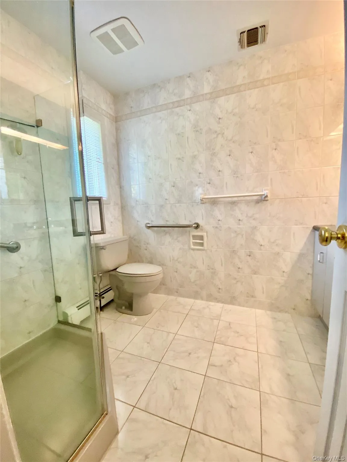Bathroom with a stall shower, a baseboard radiator, and tile walls Bathroom with a stall shower, a baseboard radiator, and tile walls