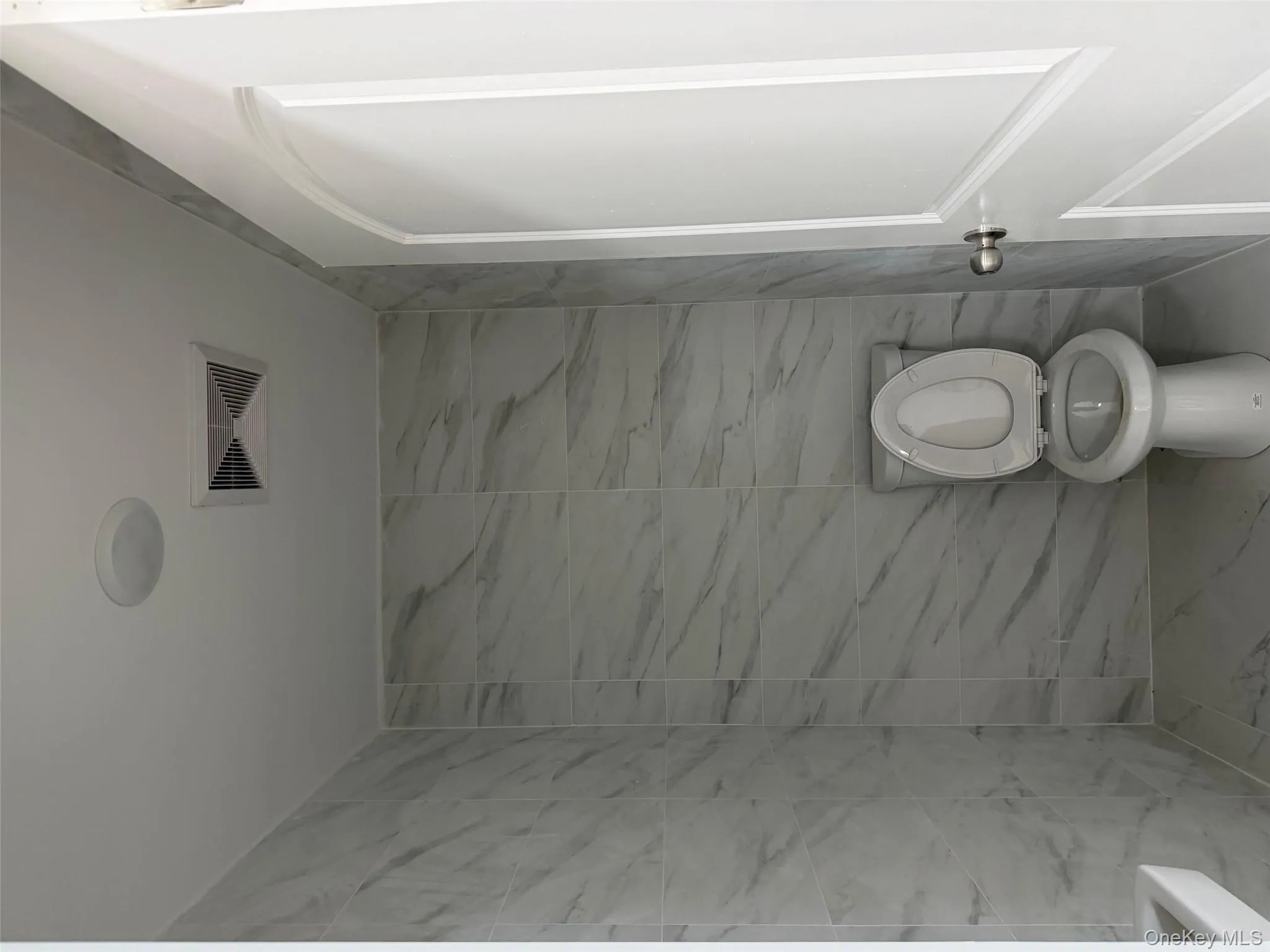 Bathroom featuring tile walls and marble finish flooring Bathroom featuring tile walls and marble finish flooring