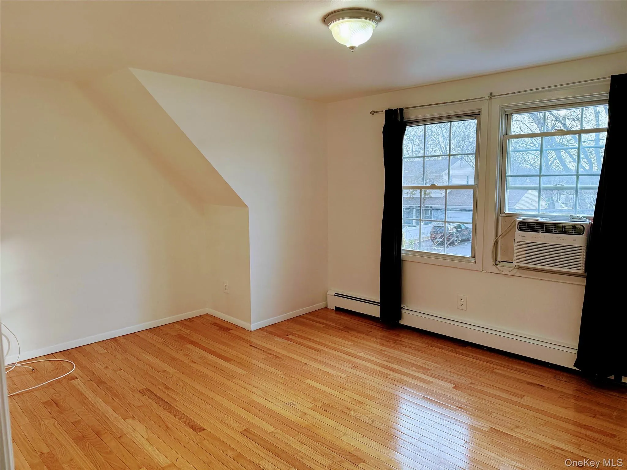 Large Bedroom #1 w/hardwood floors, Window A/C unit, and a baseboard heating unit Large Bedroom #1 w/hardwood floors, Window A/C unit, and a baseboard heating unit