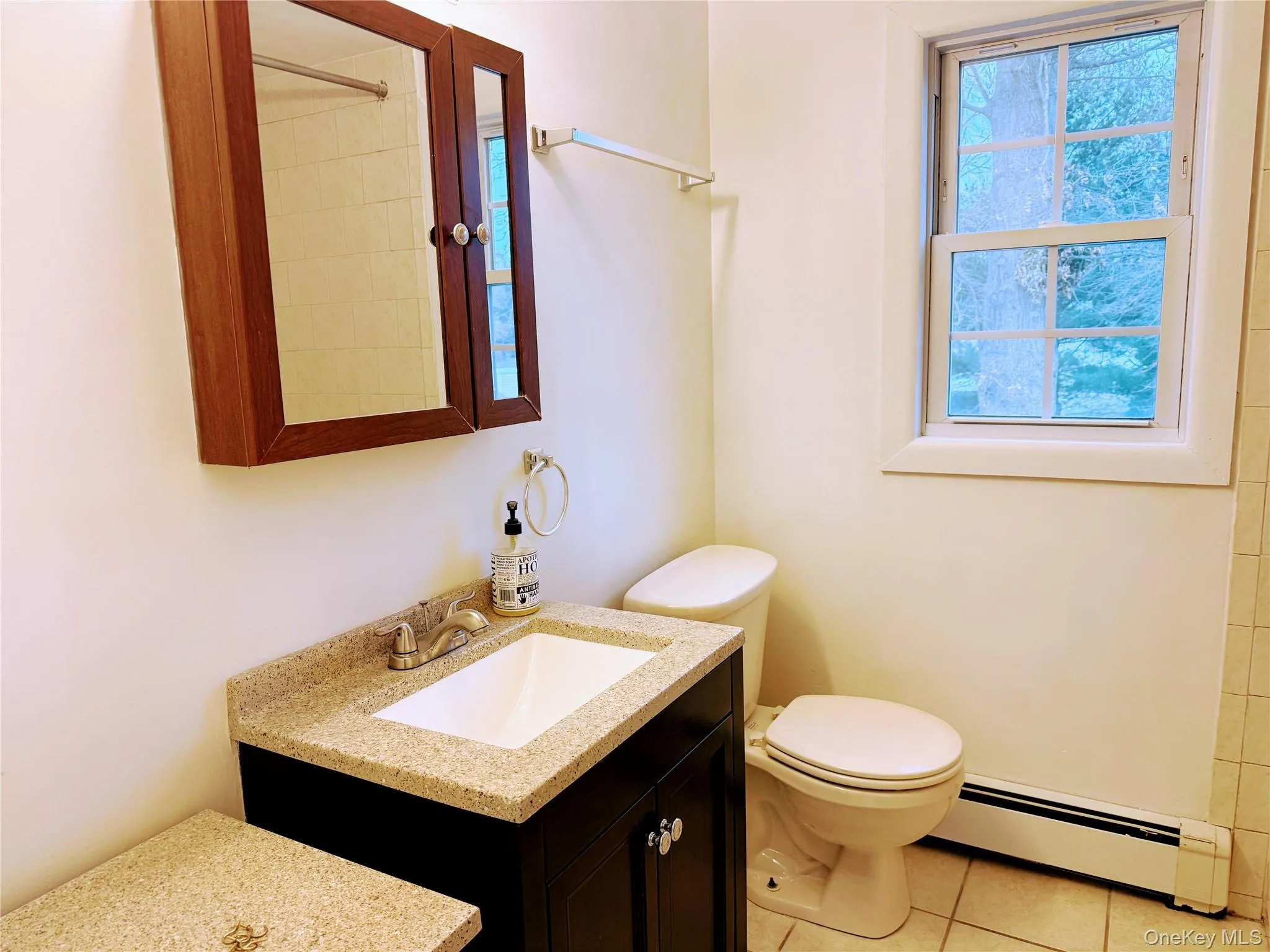 Full bath with a baseboard radiator, vanity, and light tile patterned floors Full bath with a baseboard radiator, vanity, and light tile patterned floors