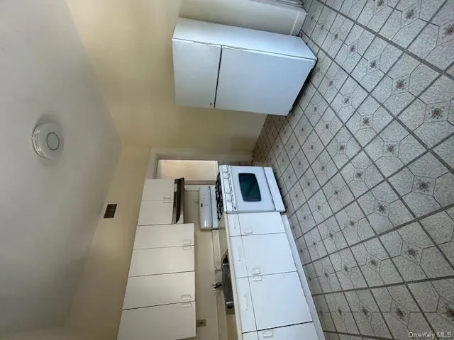 Kitchen with white range, refrigerator, white cabinets, light countertops, and light floors Kitchen with white range, refrigerator, white cabinets, light countertops, and light floors