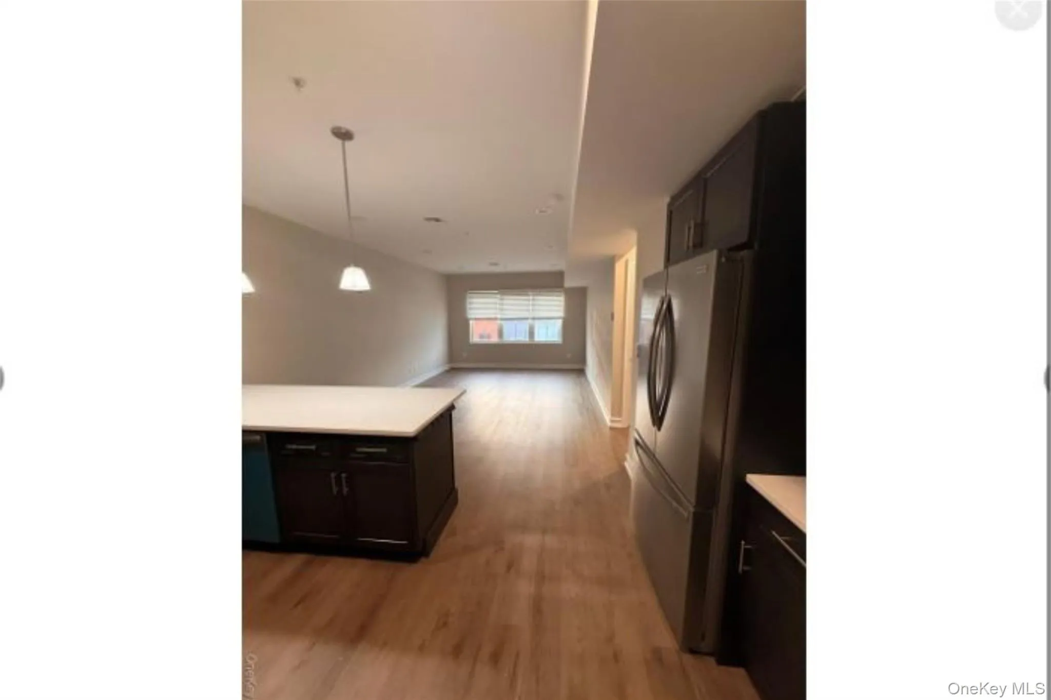 Kitchen with light countertops, freestanding refrigerator, open floor plan, light wood-style floors, and pendant lighting Kitchen with light countertops, freestanding refrigerator, open floor plan, light wood-style floors, and pendant lighting