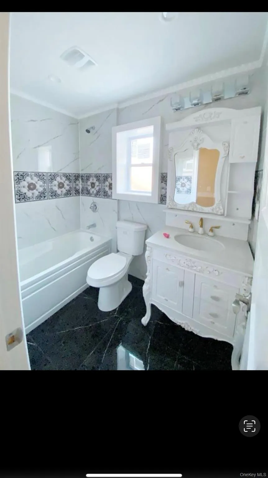 Full bath with vanity, shower / washtub combination, granite floors, and tile walls Full bath with vanity, shower / washtub combination, granite floors, and tile walls