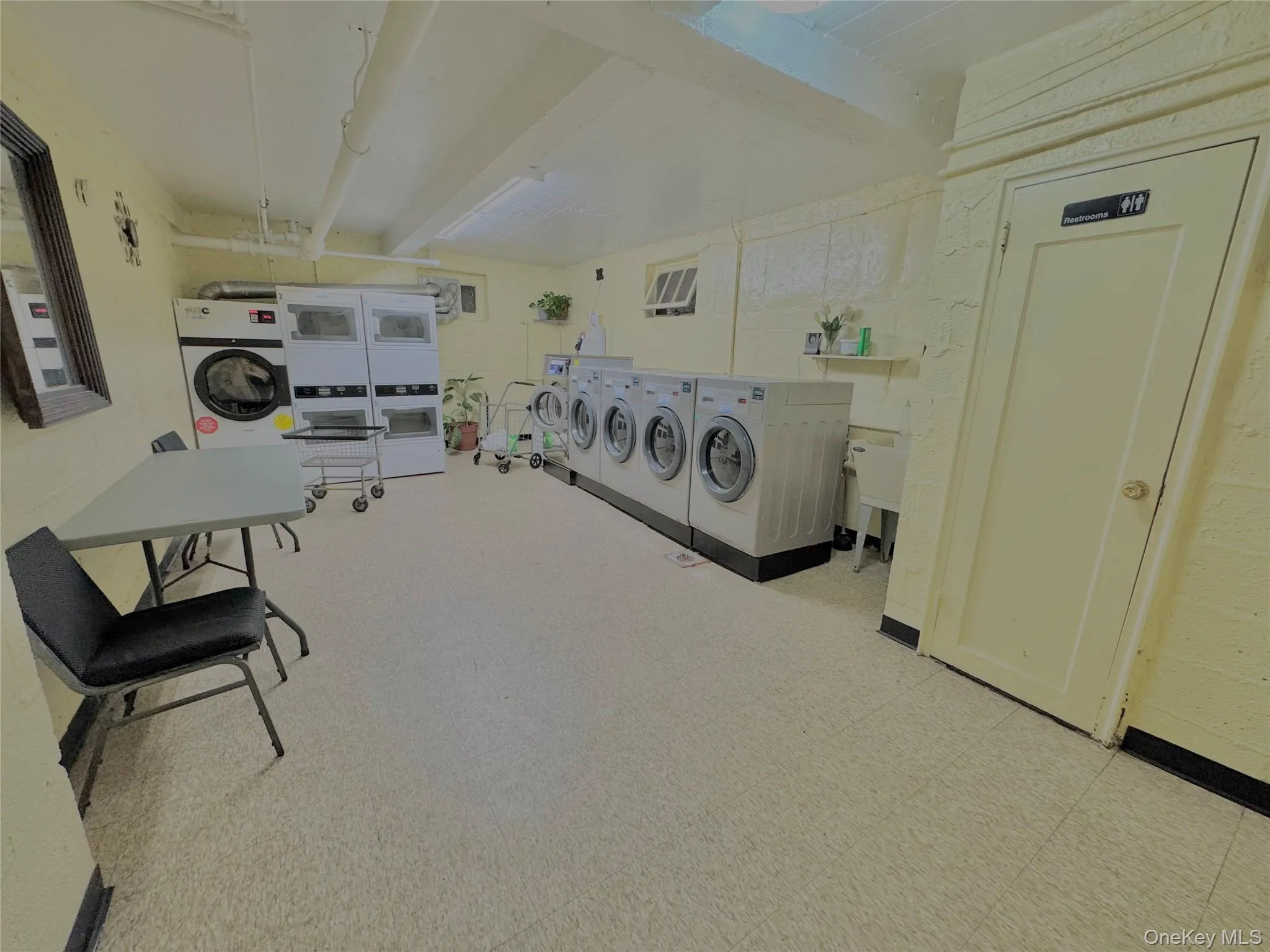 Community laundry room with beam ceiling, stacked washer / dryer, and washing machine and clothes dryer Community laundry room with beam ceiling, stacked washer / dryer, and washing machine and clothes dryer