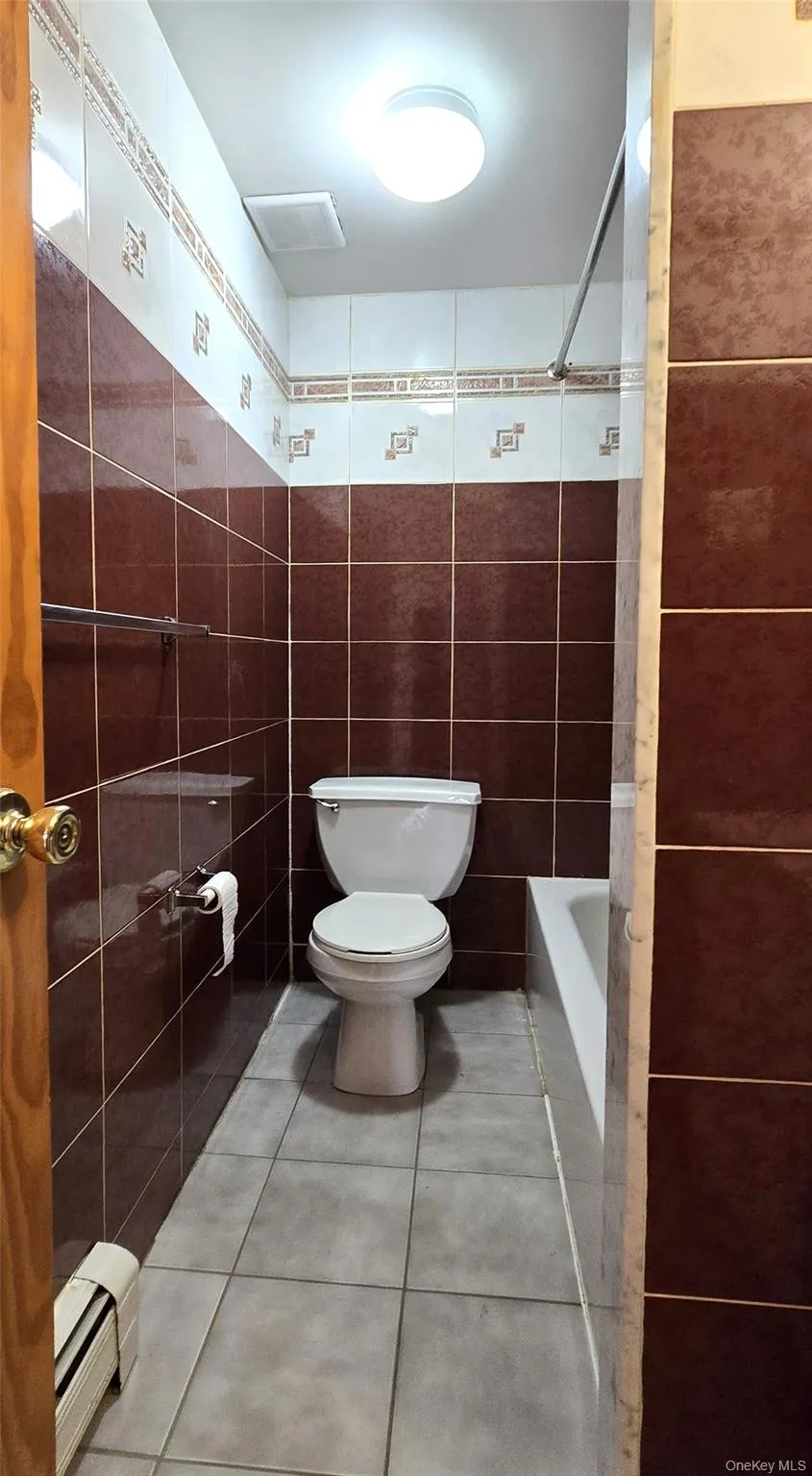 Bathroom with light tile patterned flooring, a baseboard heating unit, tile walls, and washtub / shower combination Bathroom with light tile patterned flooring, a baseboard heating unit, tile walls, and washtub / shower combination