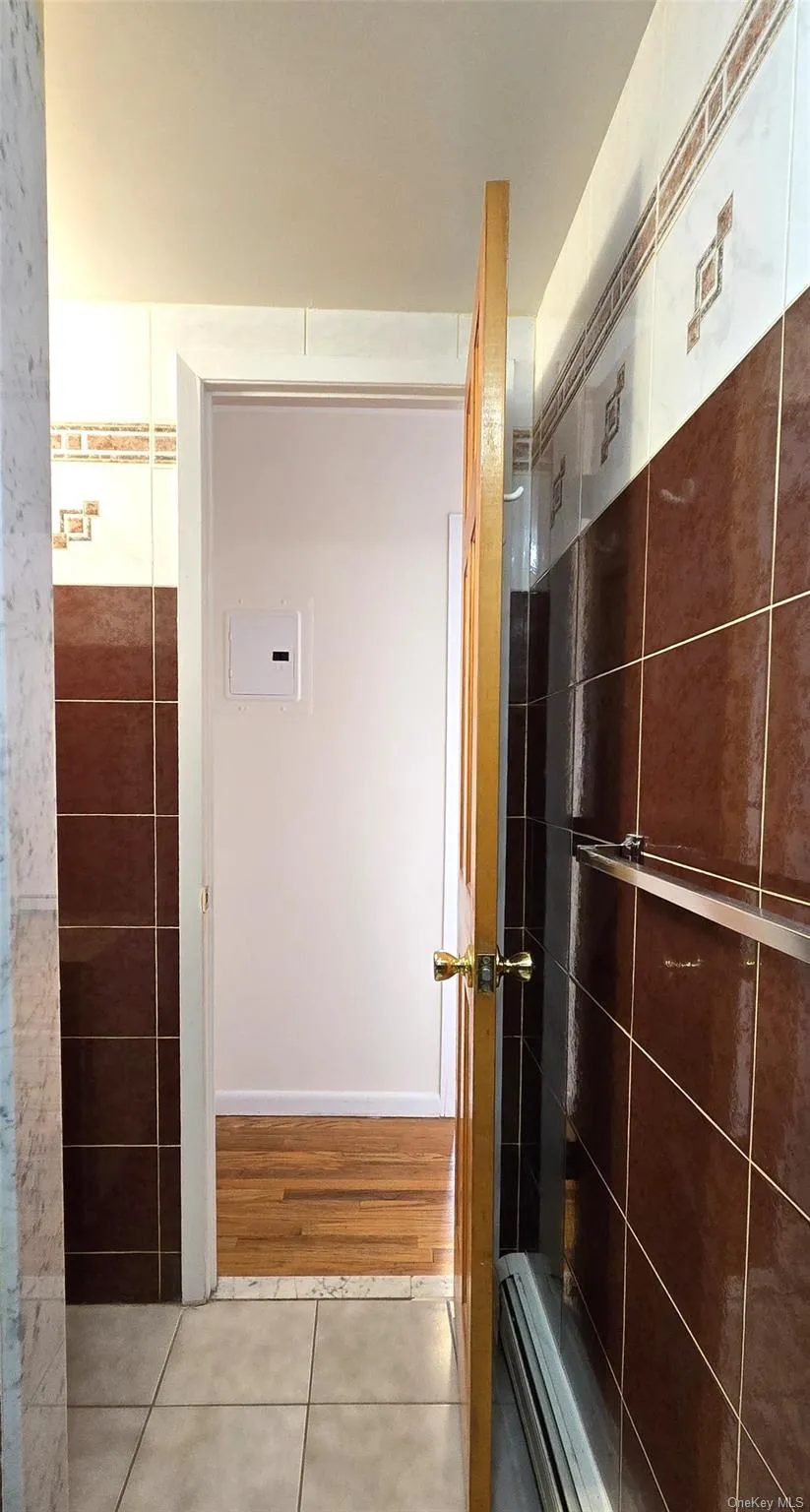 Bathroom with light tile patterned flooring, tiled shower, and baseboard heating Bathroom with light tile patterned flooring, tiled shower, and baseboard heating