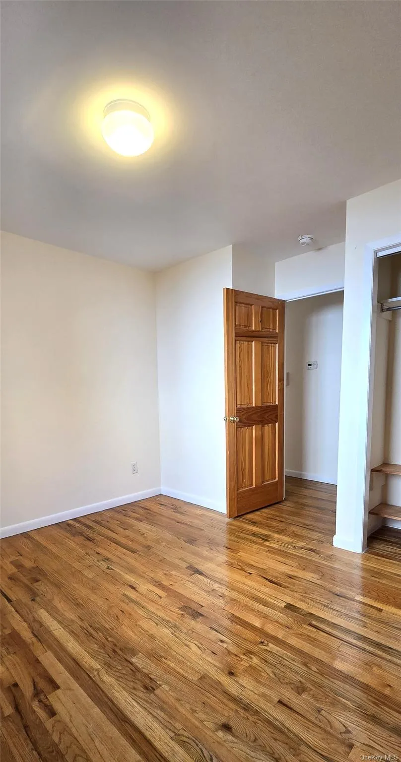 Empty room with wood-type flooring and baseboards Empty room with wood-type flooring and baseboards