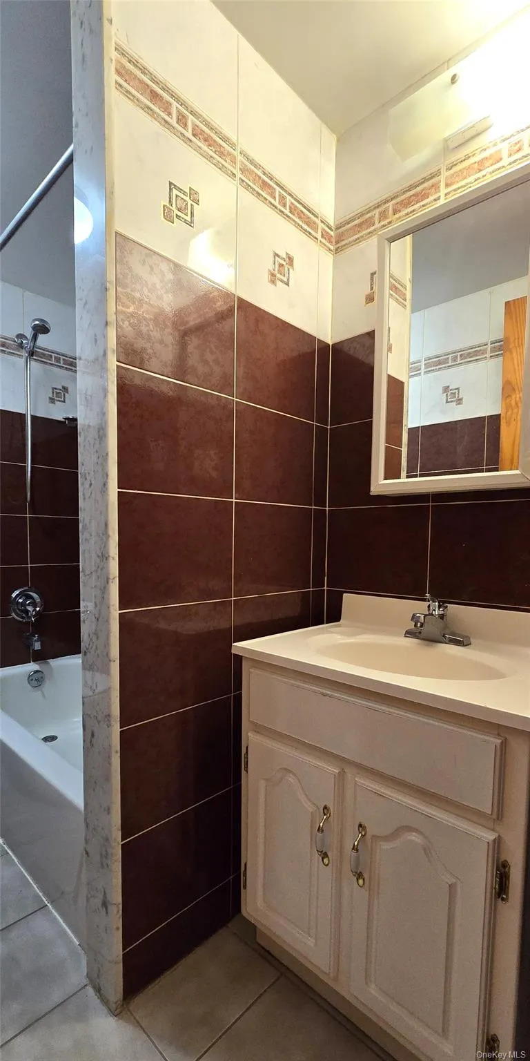 Full bath with vanity, tile walls, light tile patterned floors, and shower / tub combination Full bath with vanity, tile walls, light tile patterned floors, and shower / tub combination