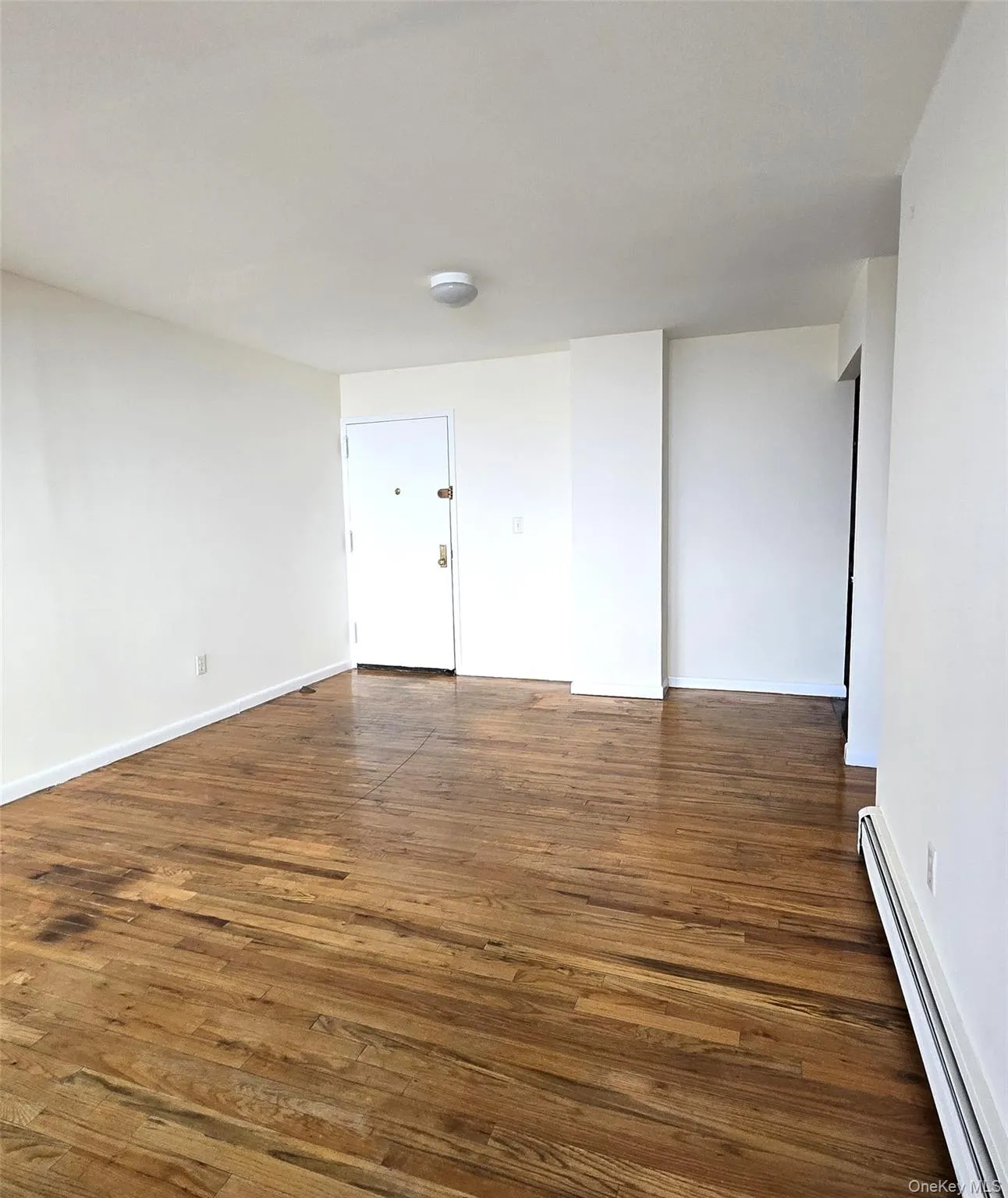 Spare room with a baseboard heating unit and hardwood / wood-style floors Spare room with a baseboard heating unit and hardwood / wood-style floors