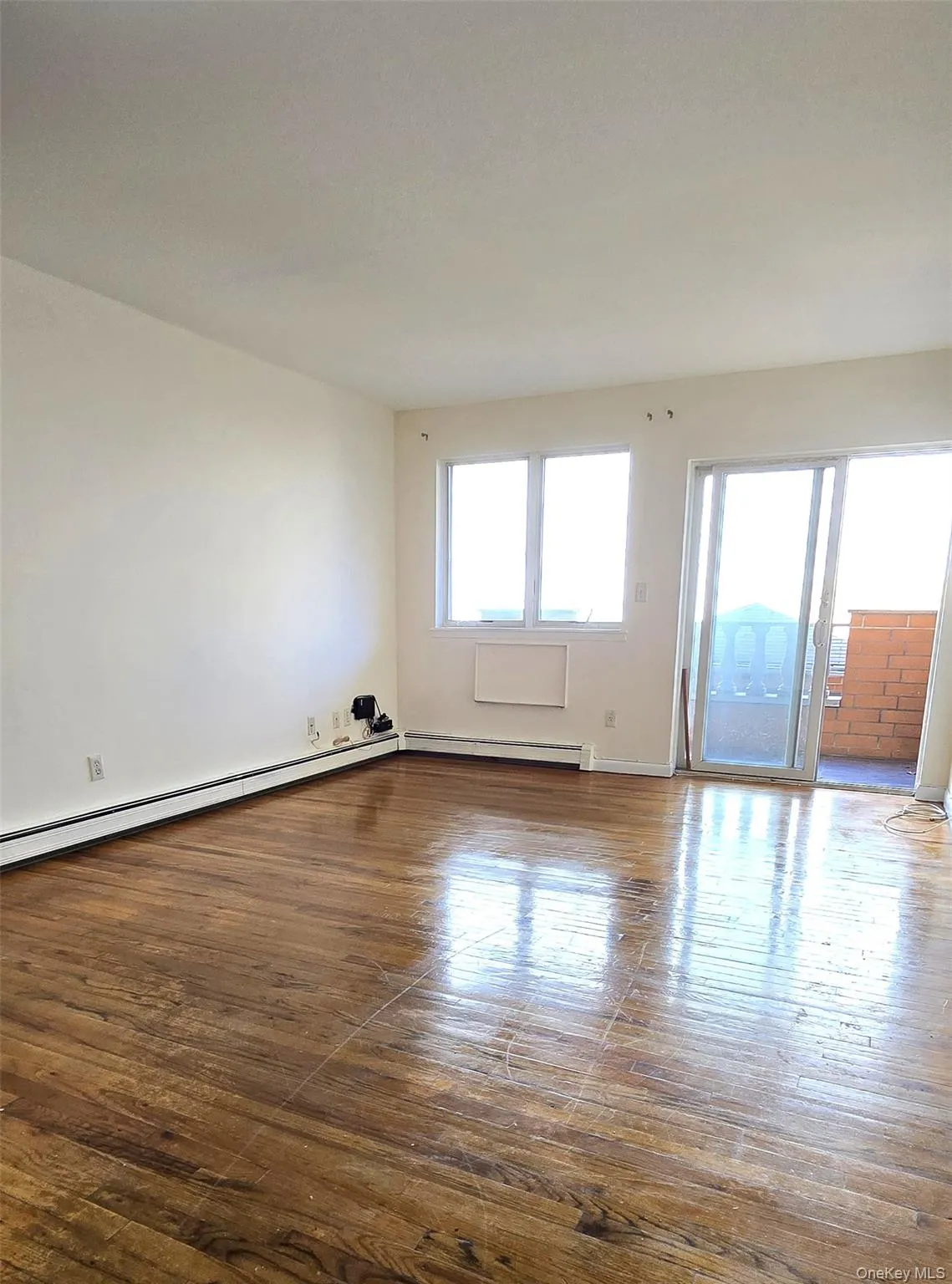 Unfurnished room with dark wood finished floors and a baseboard radiator Unfurnished room with dark wood finished floors and a baseboard radiator
