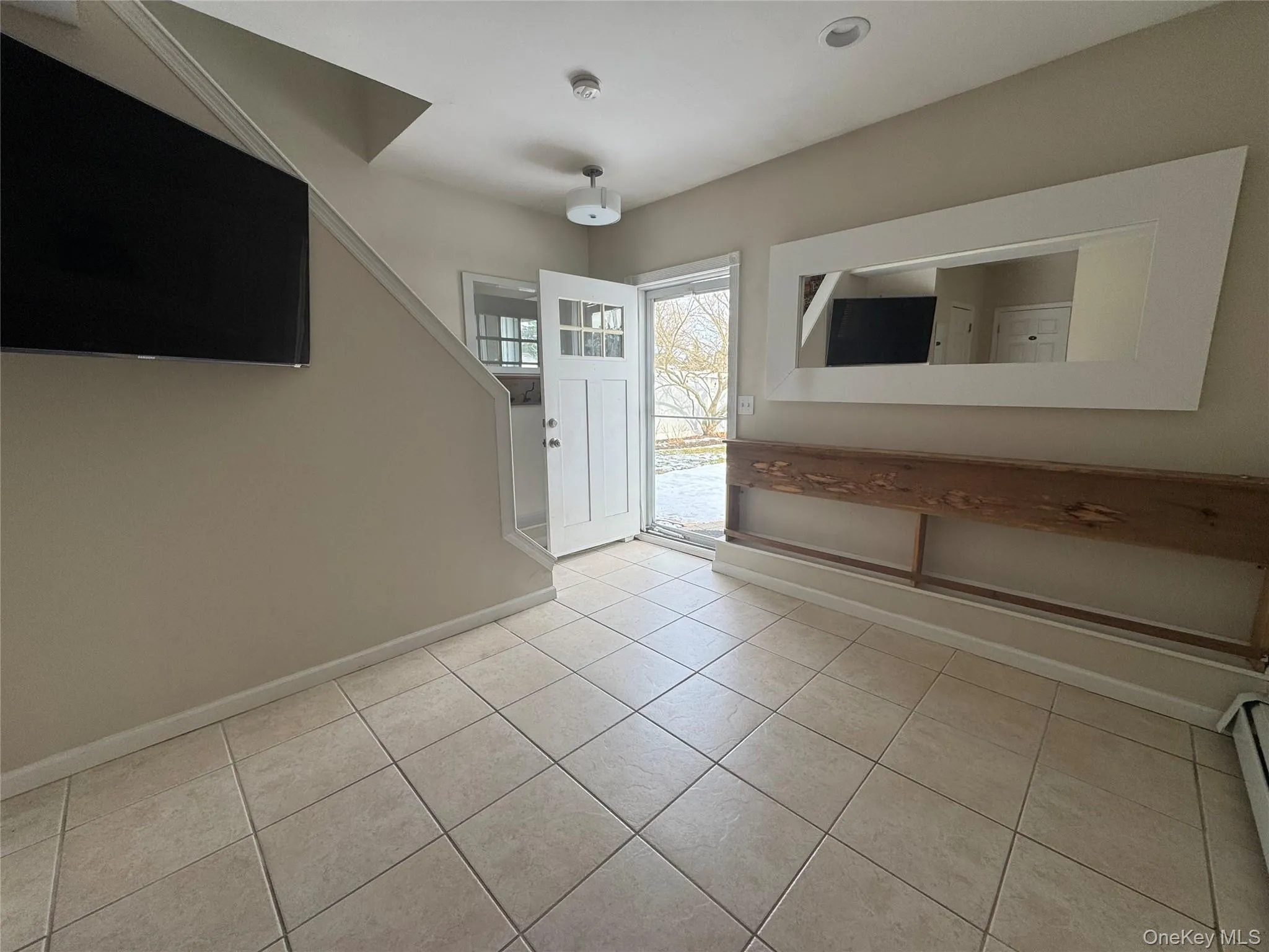 Foyer entrance with light tile patterned floors and a baseboard radiator Foyer entrance with light tile patterned floors and a baseboard radiator