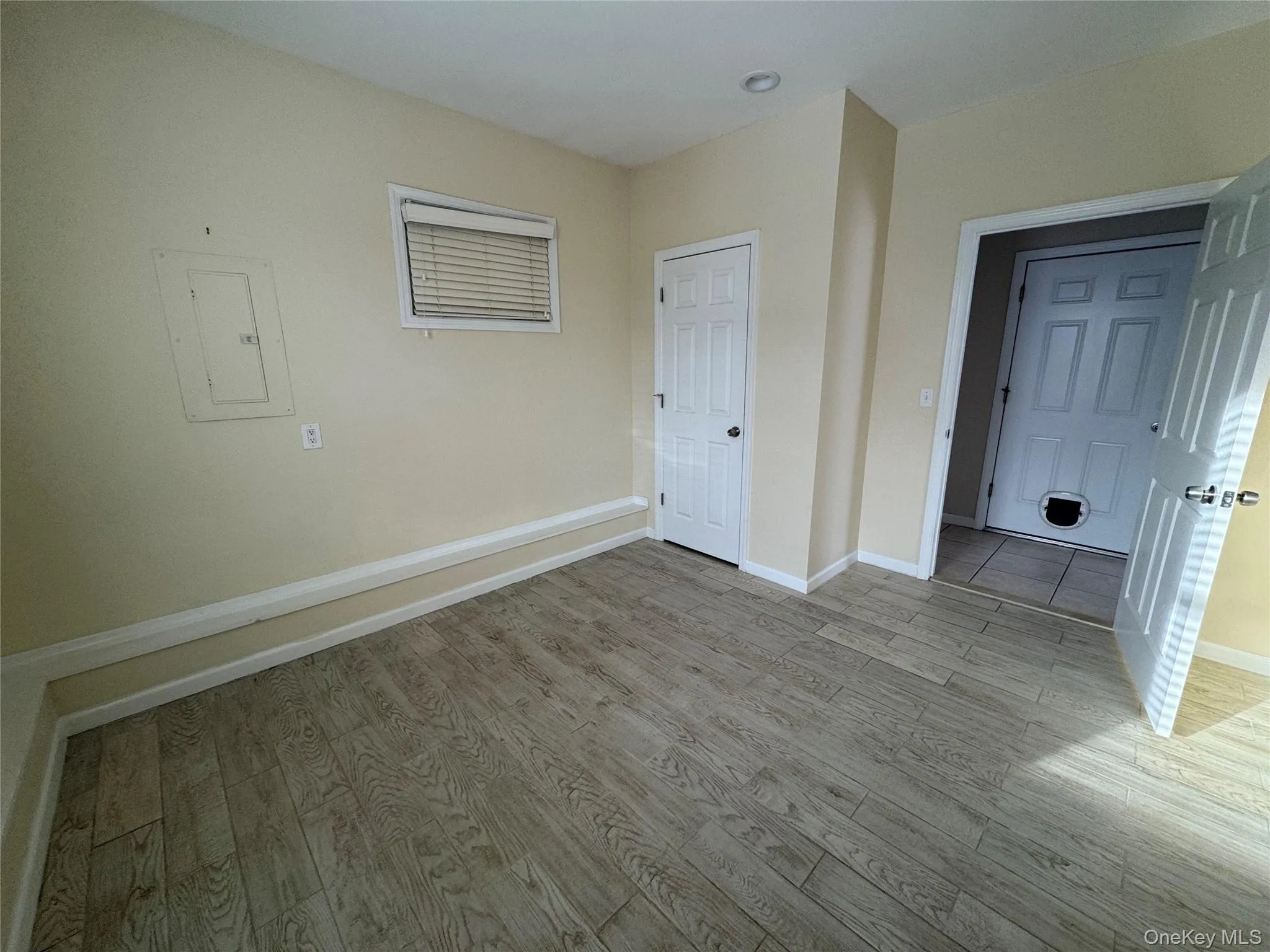 Unfurnished bedroom featuring electric panel and light wood finished floors Unfurnished bedroom featuring electric panel and light wood finished floors