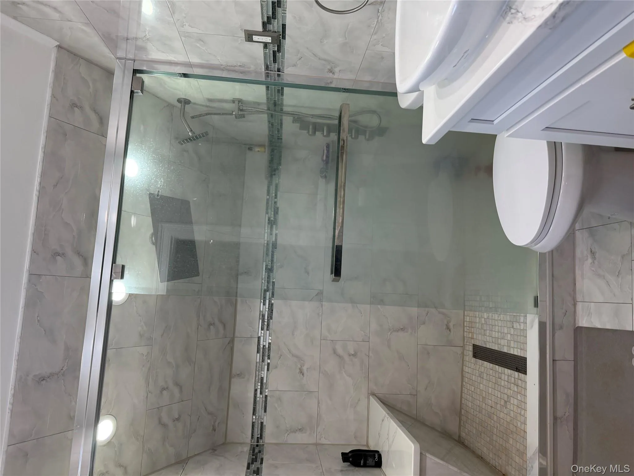 Full bathroom featuring vanity, a stall shower, and marble look tiles Full bathroom featuring vanity, a stall shower, and marble look tiles