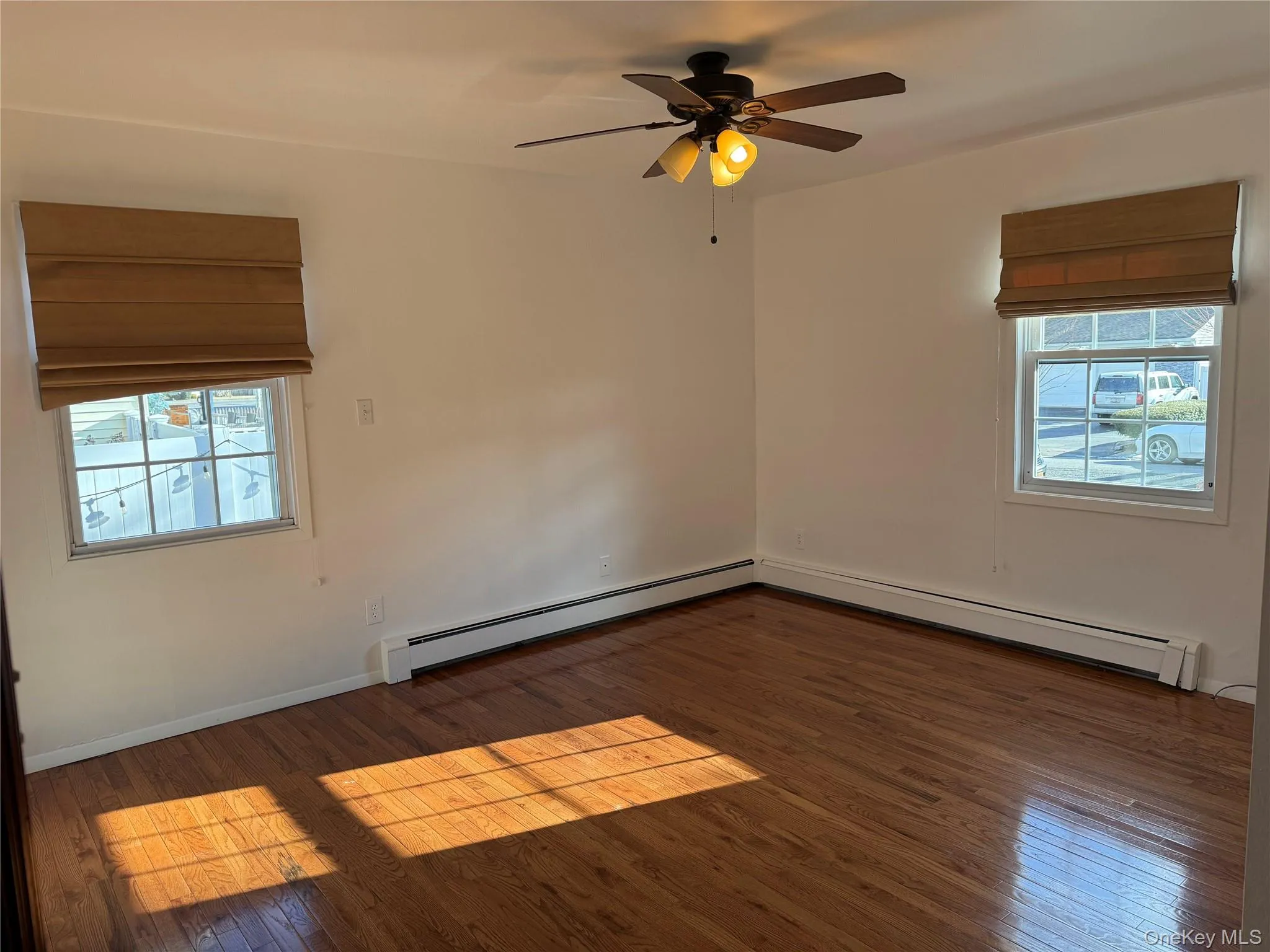 Primary bedroom with hard wood floors and baseboard heat and fan Primary bedroom with hard wood floors and baseboard heat and fan