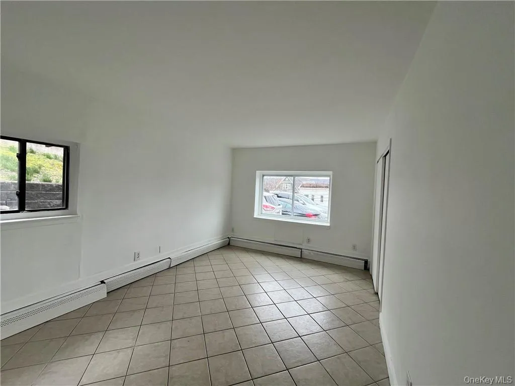 Empty room with a baseboard heating unit and light tile patterned flooring Empty room with a baseboard heating unit and light tile patterned flooring