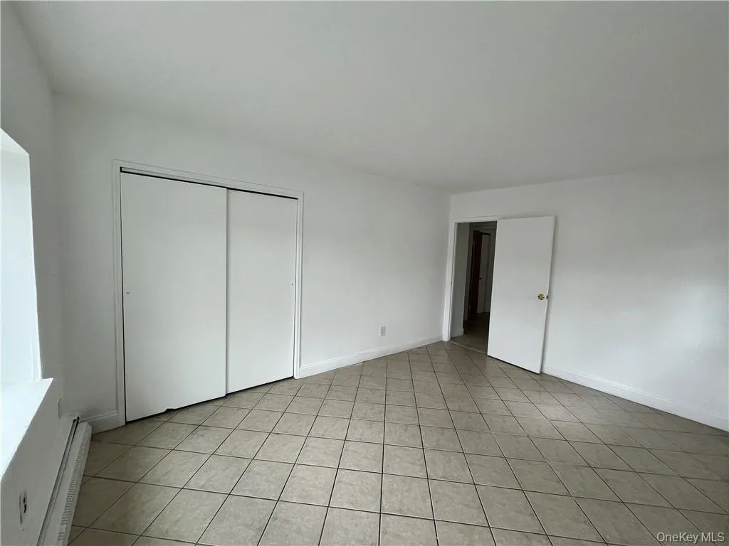 Unfurnished bedroom with a baseboard heating unit and a closet Unfurnished bedroom with a baseboard heating unit and a closet