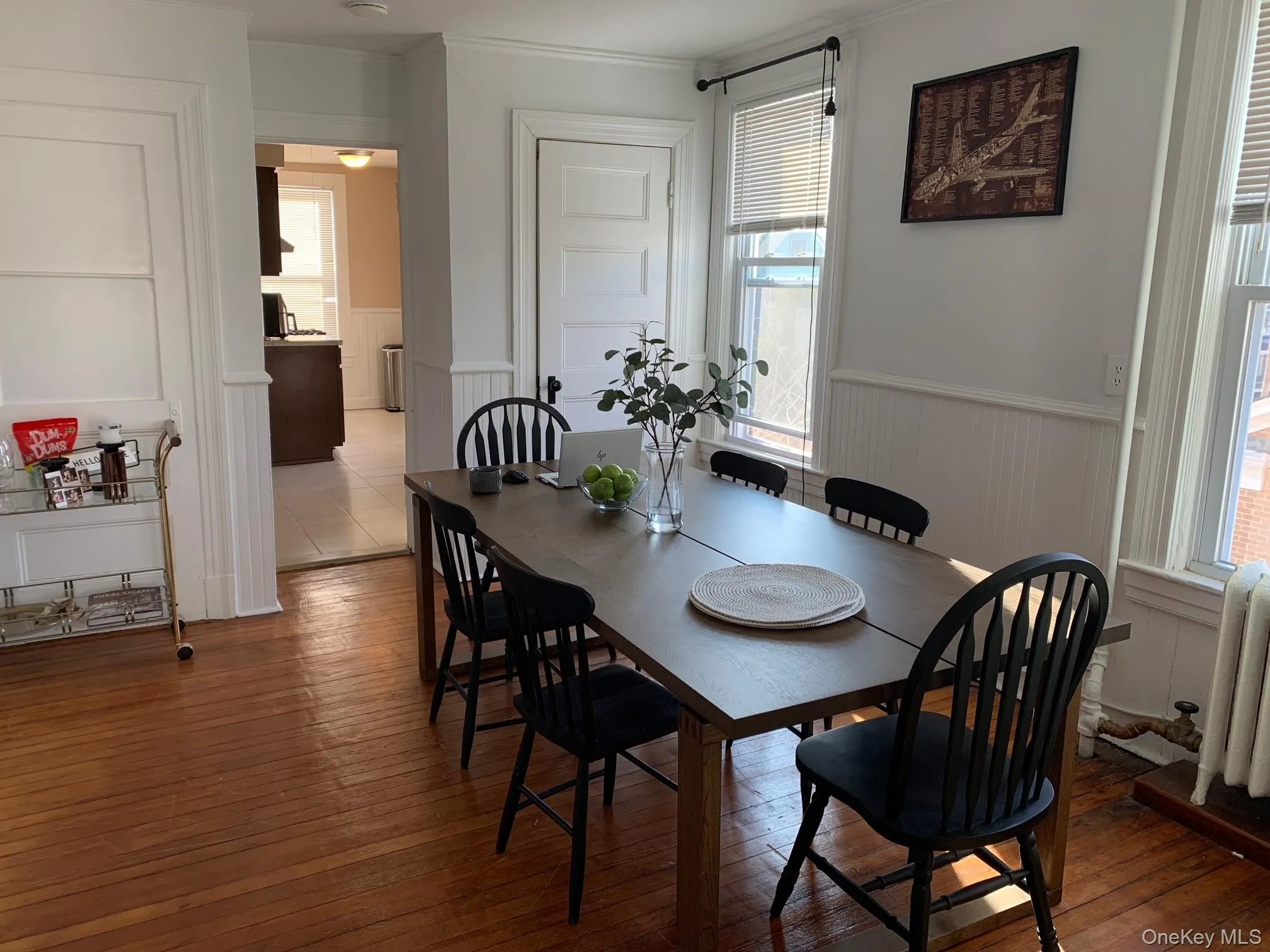 Dining space featuring a wainscoted wall, hardwood / wood-style flooring, a decorative wall, crown molding, and radiator heating unit Dining space featuring a wainscoted wall, hardwood / wood-style flooring, a decorative wall, crown molding, and radiator heating unit