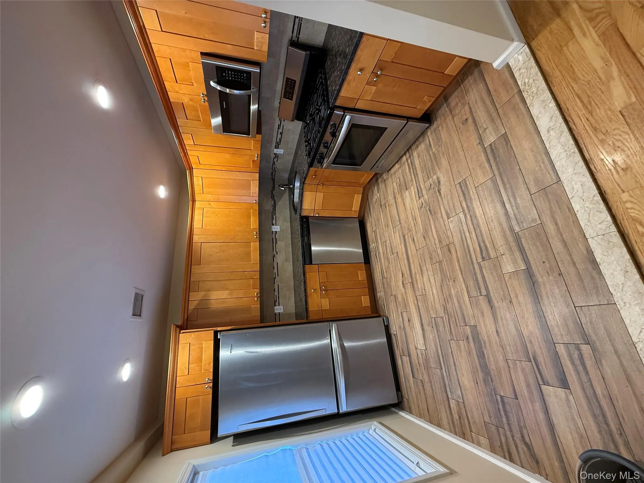 Kitchen featuring stove, refrigerator, brown cabinetry, dark stone counters, and recessed lighting Kitchen featuring stove, refrigerator, brown cabinetry, dark stone counters, and recessed lighting