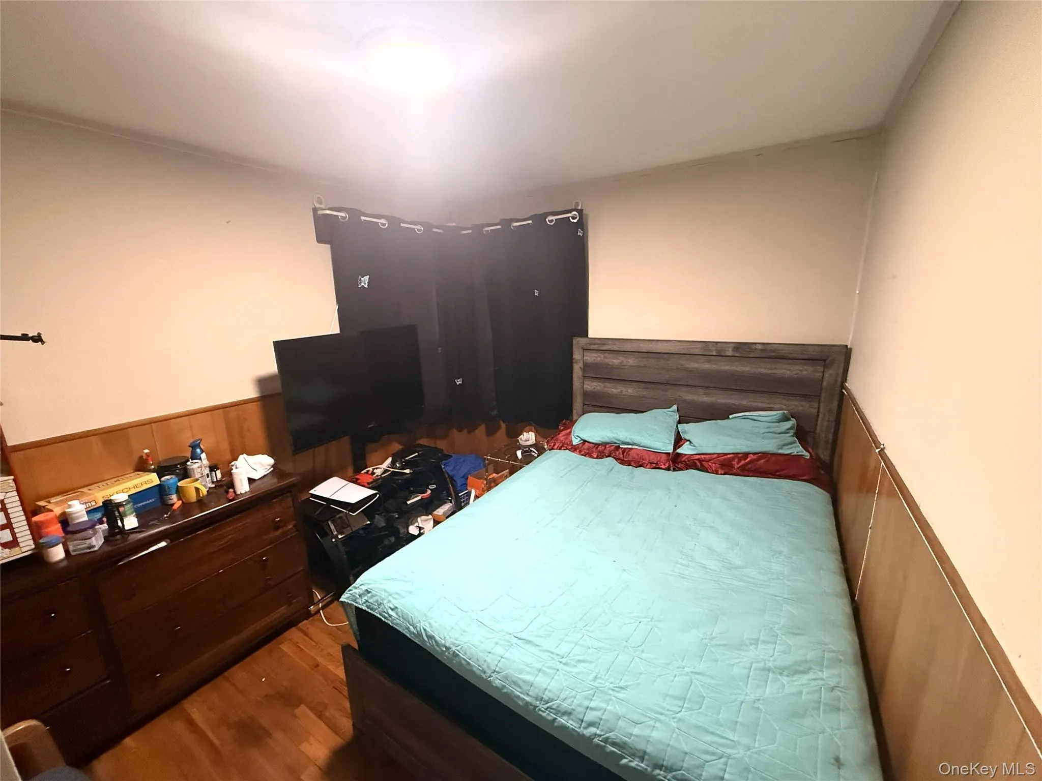 Bedroom featuring a wainscoted wall, dark wood-style floors, and wood walls Bedroom featuring a wainscoted wall, dark wood-style floors, and wood walls