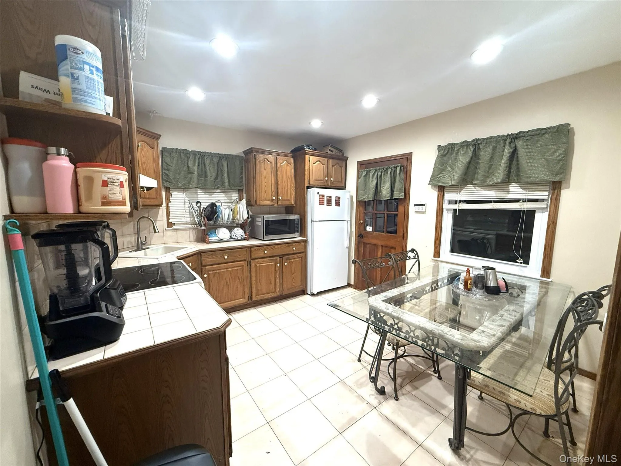 Kitchen featuring tile countertops, white appliances, recessed lighting, light tile patterned floors, and tasteful backsplash Kitchen featuring tile countertops, white appliances, recessed lighting, light tile patterned floors, and tasteful backsplash