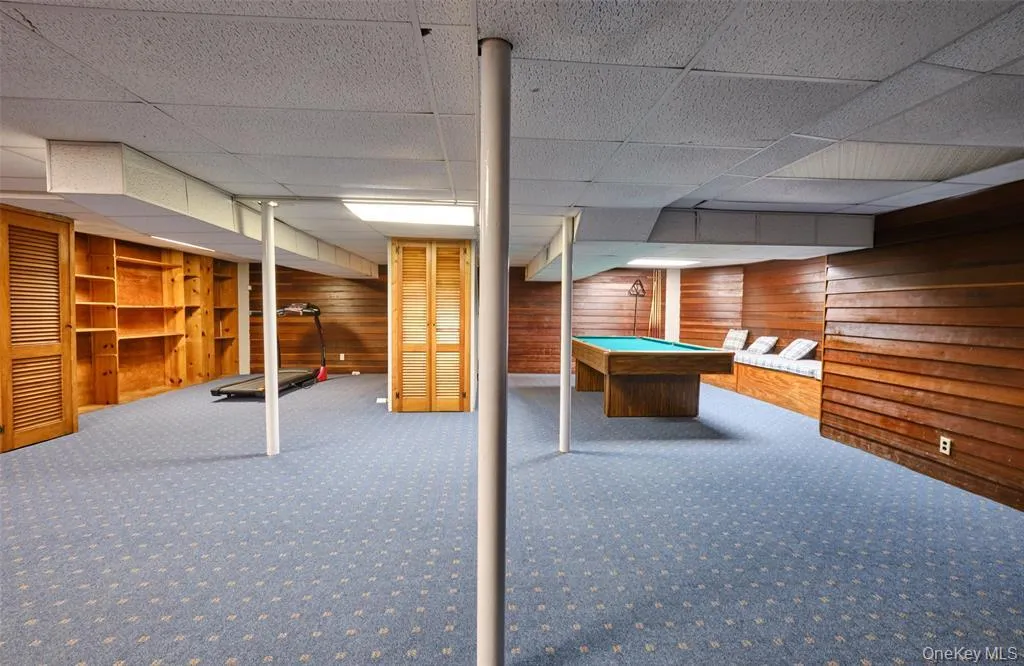 Finished below grade area with carpet floors, wood walls, and billiards Finished below grade area with carpet floors, wood walls, and billiards