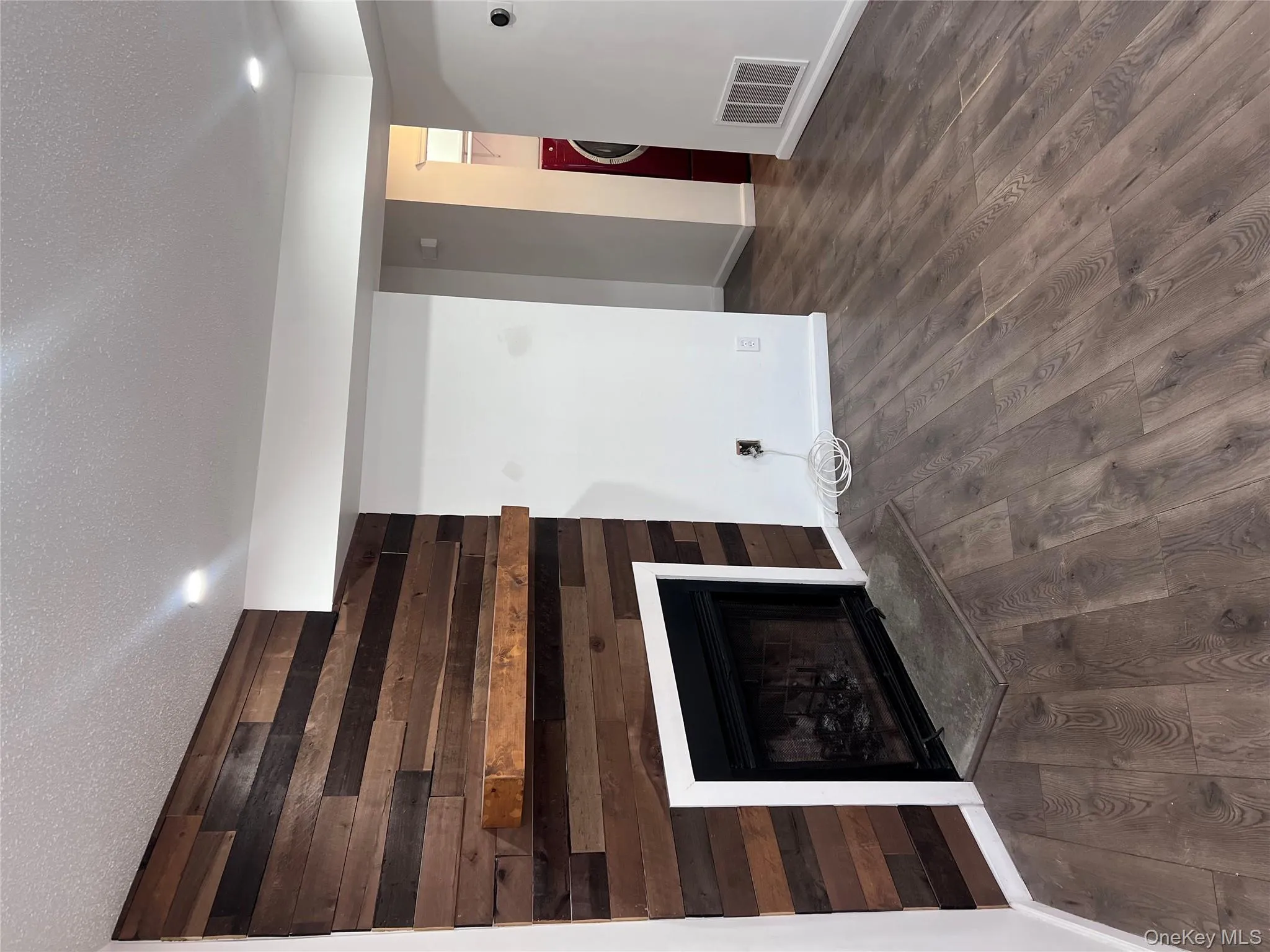 Unfurnished living room featuring wooden walls, dark hardwood / wood-style flooring, and a textured ceiling Unfurnished living room featuring wooden walls, dark hardwood / wood-style flooring, and a textured ceiling