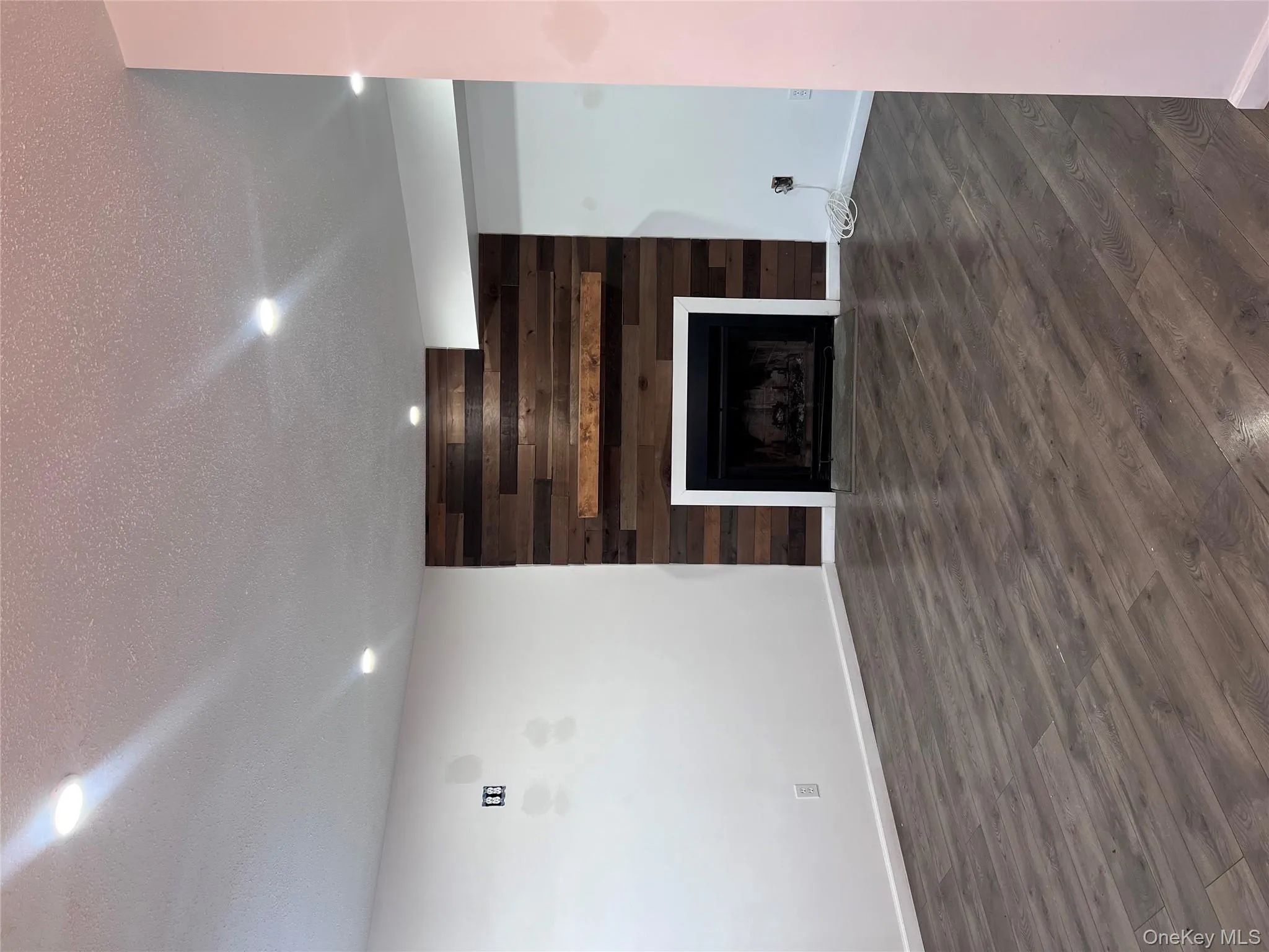 Unfurnished living room with dark hardwood / wood-style flooring, wood walls, a fireplace, and a textured ceiling Unfurnished living room with dark hardwood / wood-style flooring, wood walls, a fireplace, and a textured ceiling