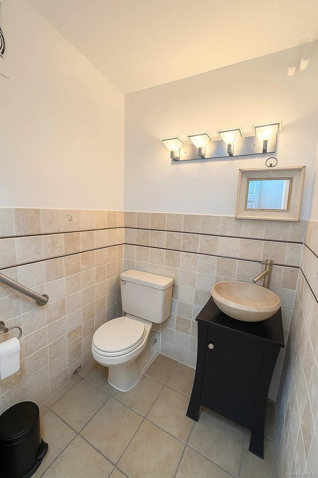 Half bathroom featuring tile walls, wainscoting, vanity, and tile patterned floors Half bathroom featuring tile walls, wainscoting, vanity, and tile patterned floors