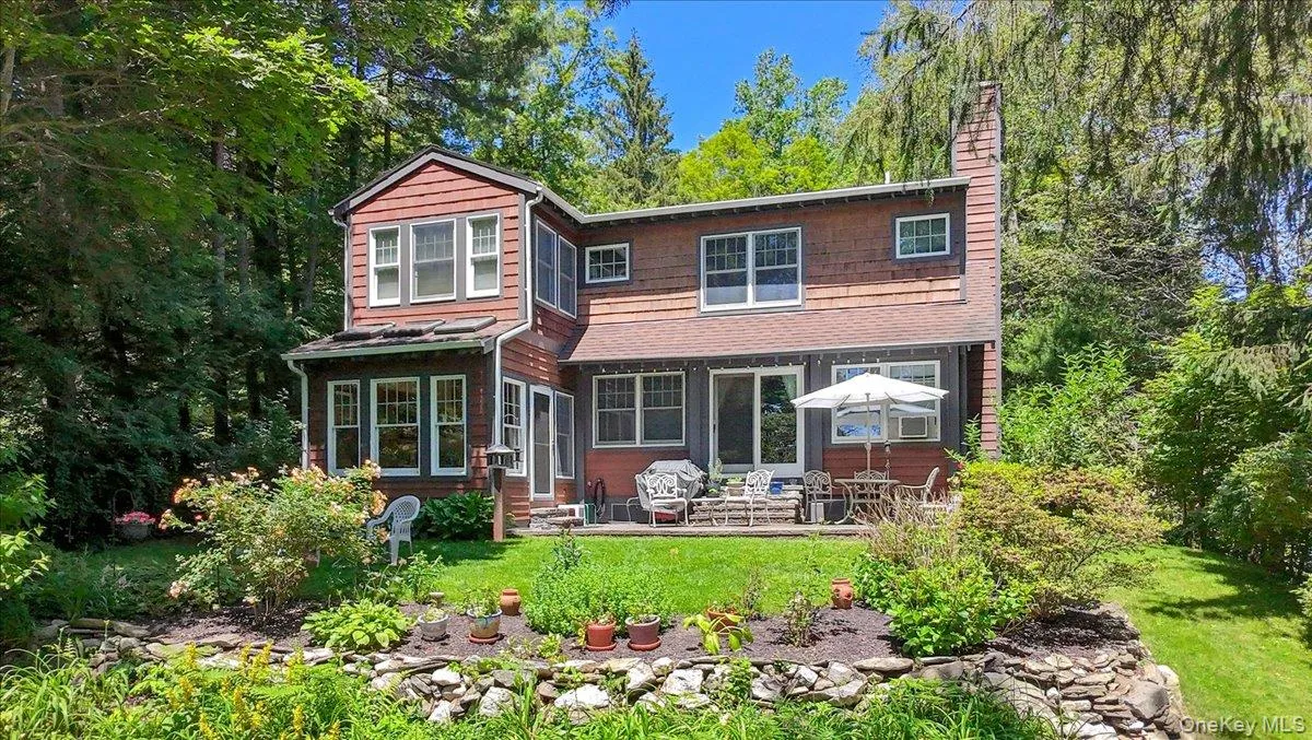 Back of property with entry steps, a chimney, a lawn, and a patio Back of property with entry steps, a chimney, a lawn, and a patio