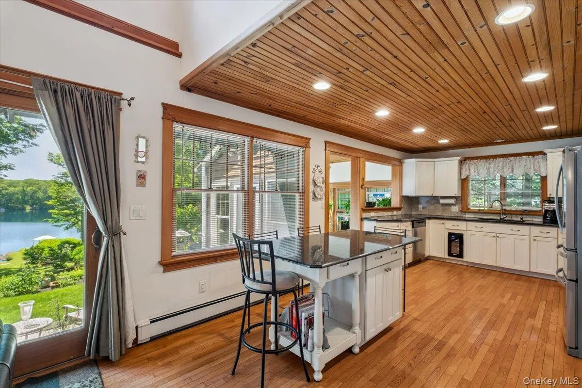 Kitchen with water views, stainless steel appliances, baseboard heating, white cabinets, light wood finished floors, and wooden ceiling Kitchen with water views, stainless steel appliances, baseboard heating, white cabinets, light wood finished floors, and wooden ceiling