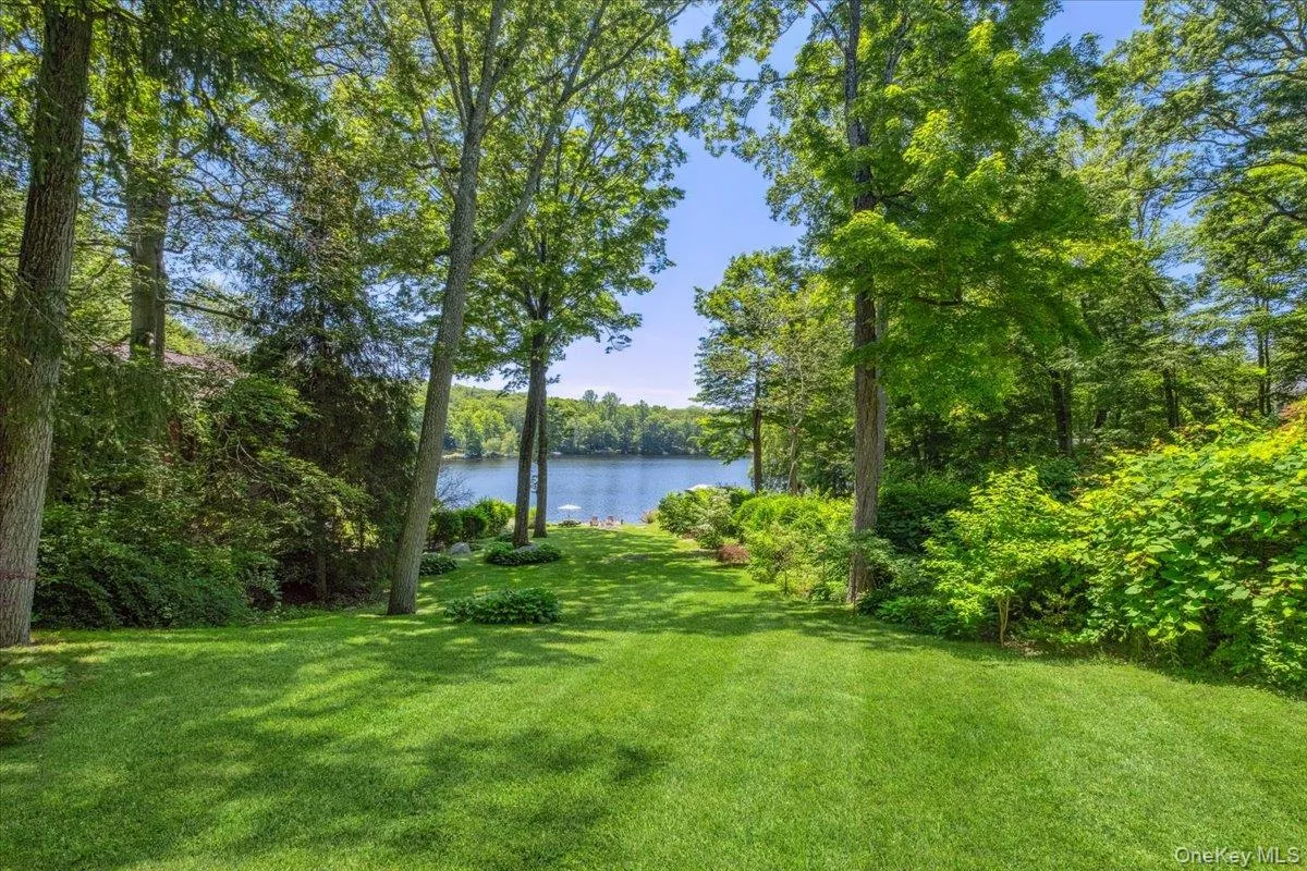 View of green lawn featuring a water view and a wooded view View of green lawn featuring a water view and a wooded view