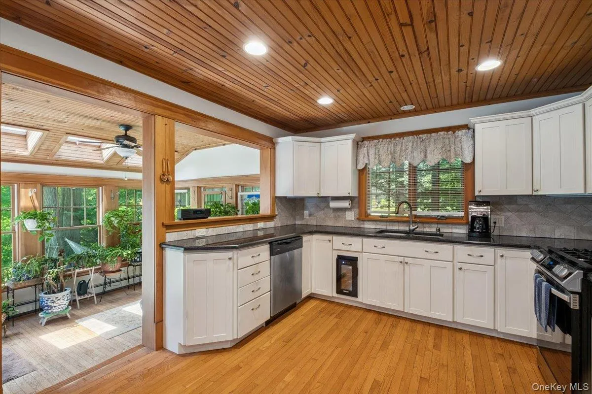 Kitchen with appliances with stainless steel finishes, wood ceiling, white cabinetry, a ceiling fan, and dark countertops Kitchen with appliances with stainless steel finishes, wood ceiling, white cabinetry, a ceiling fan, and dark countertops