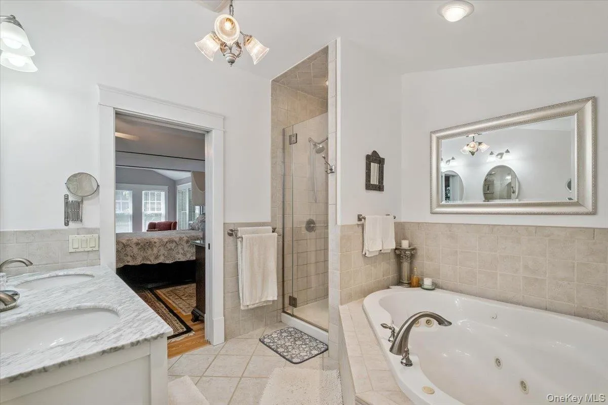 Full bathroom featuring tile patterned floors, a stall shower, a jetted tub, ensuite bathroom, and double vanity Full bathroom featuring tile patterned floors, a stall shower, a jetted tub, ensuite bathroom, and double vanity