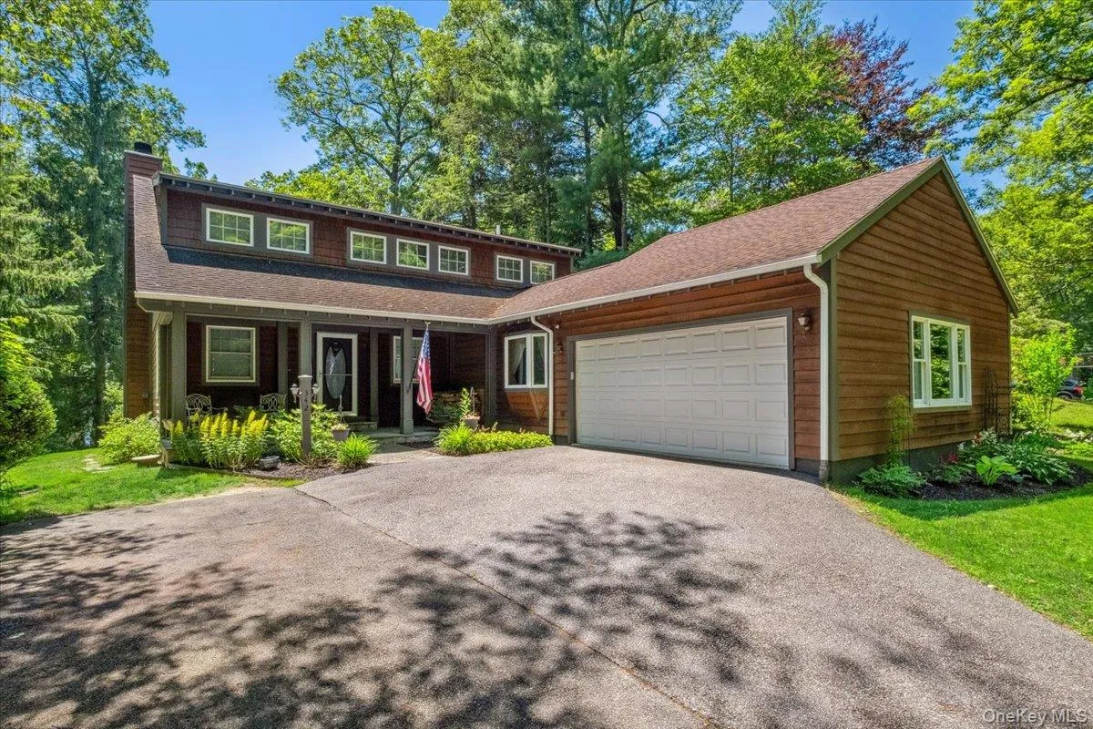 View of front of house with a garage, driveway, a chimney, covered porch, and a shingled roof View of front of house with a garage, driveway, a chimney, covered porch, and a shingled roof