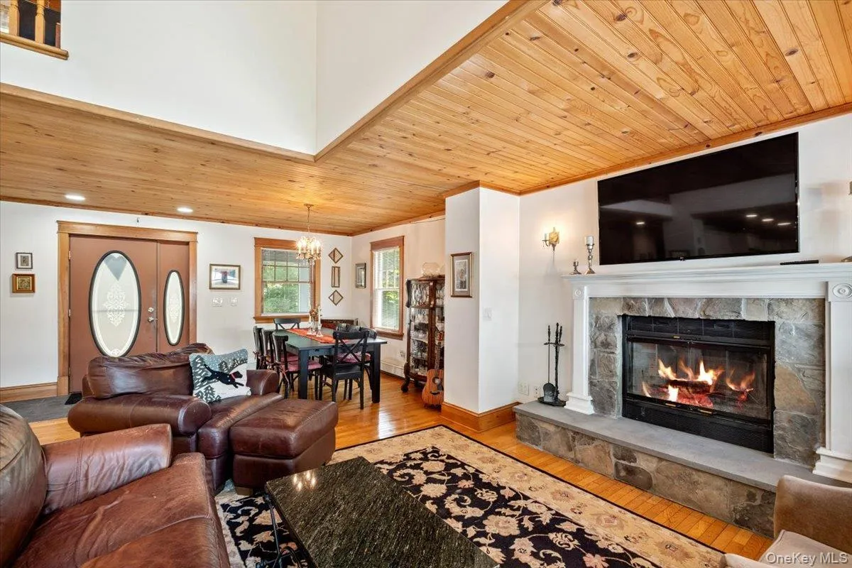 Living area featuring wood-type flooring, a chandelier, wood ceiling, a fireplace, and crown molding Living area featuring wood-type flooring, a chandelier, wood ceiling, a fireplace, and crown molding
