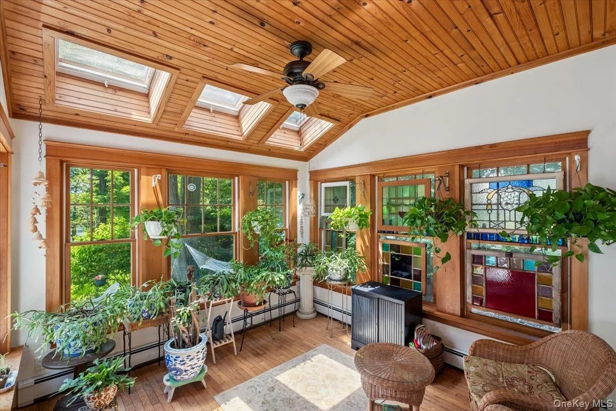 Sunroom featuring a skylight, water views, a vaulted ceiling, and baseboard heating Sunroom featuring a skylight, water views, a vaulted ceiling, and baseboard heating
