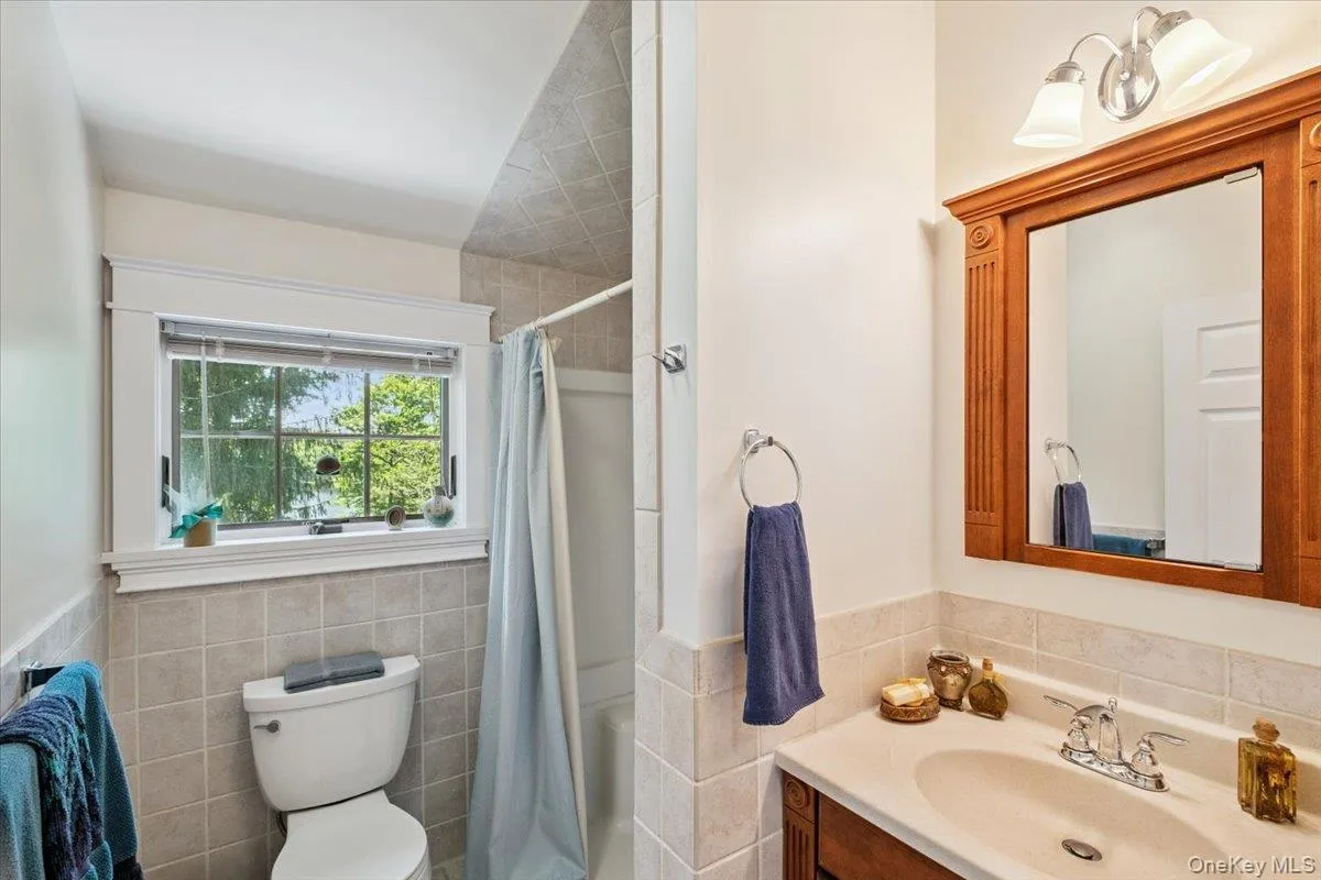 Bathroom with tile walls, vanity, shower / bath combo with shower curtain, and wainscoting Bathroom with tile walls, vanity, shower / bath combo with shower curtain, and wainscoting