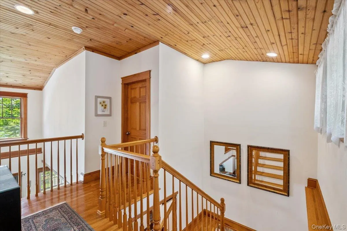 Hallway with an upstairs landing, wood finished floors, ornamental molding, wooden ceiling, and recessed lighting Hallway with an upstairs landing, wood finished floors, ornamental molding, wooden ceiling, and recessed lighting