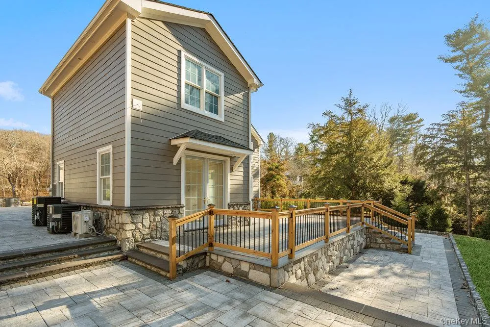 Back of property featuring a wooden deck, stone siding, and a patio area Back of property featuring a wooden deck, stone siding, and a patio area