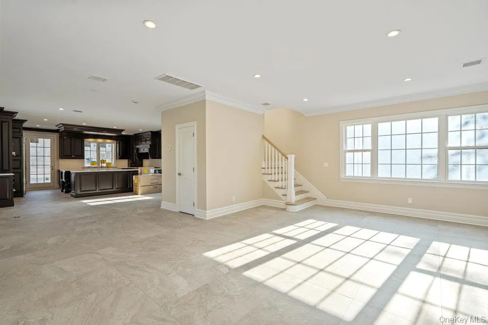 Unfurnished living room with crown molding, stairway, and recessed lighting Unfurnished living room with crown molding, stairway, and recessed lighting