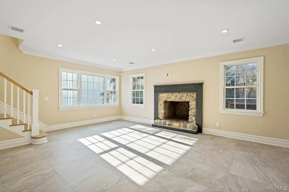 Unfurnished living room featuring stairway, a stone fireplace, crown molding, and recessed lighting Unfurnished living room featuring stairway, a stone fireplace, crown molding, and recessed lighting