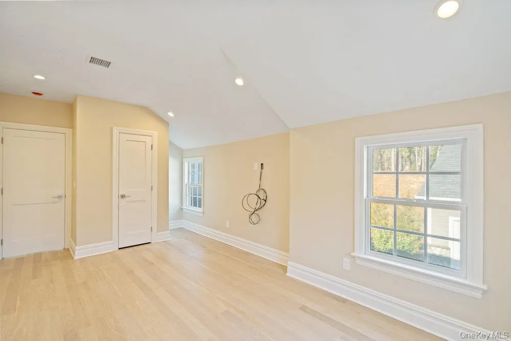 Unfurnished room featuring recessed lighting, light wood-style flooring, and vaulted ceiling Unfurnished room featuring recessed lighting, light wood-style flooring, and vaulted ceiling