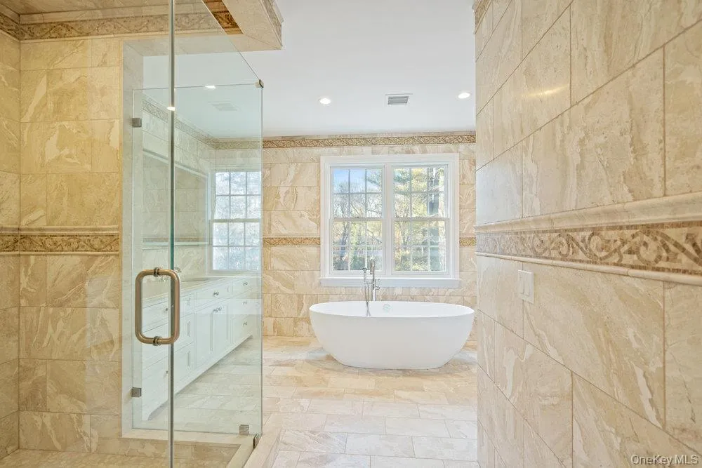 Bathroom featuring a freestanding bath, a shower stall, tile walls, and recessed lighting Bathroom featuring a freestanding bath, a shower stall, tile walls, and recessed lighting
