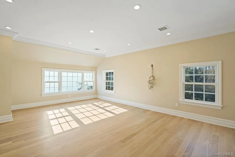 Empty room with light wood finished floors, ornamental molding, and recessed lighting Empty room with light wood finished floors, ornamental molding, and recessed lighting