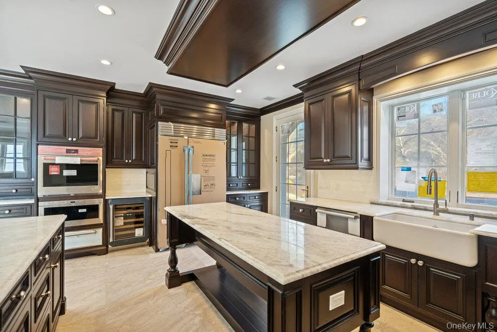 Kitchen featuring dark brown cabinetry, stainless steel appliances, wine cooler, backsplash, and recessed lighting Kitchen featuring dark brown cabinetry, stainless steel appliances, wine cooler, backsplash, and recessed lighting