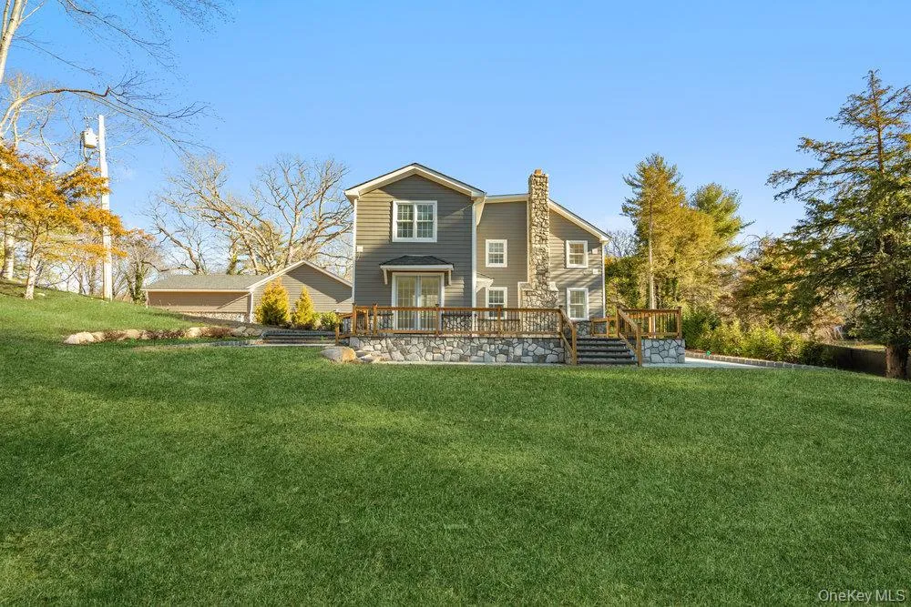 Back of property with a lawn, a chimney, and a deck Back of property with a lawn, a chimney, and a deck