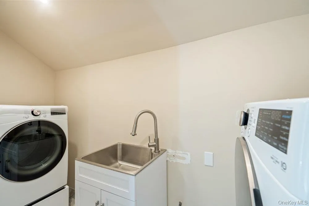 Washroom featuring washer / clothes dryer, lofted ceiling, and cabinet space Washroom featuring washer / clothes dryer, lofted ceiling, and cabinet space