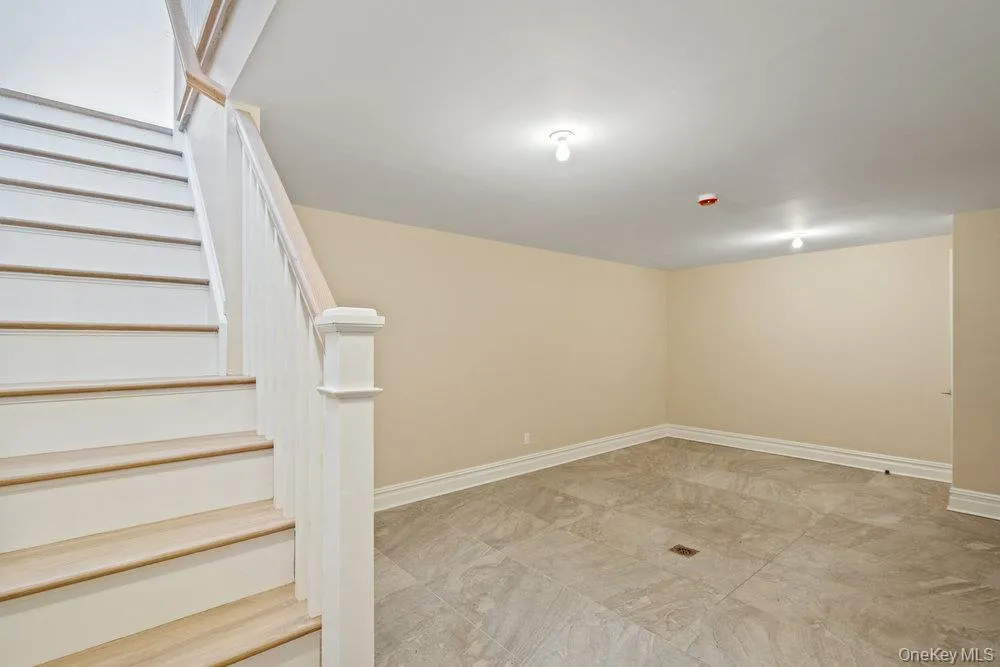Below grade area featuring stairs and light marble finish floors Below grade area featuring stairs and light marble finish floors