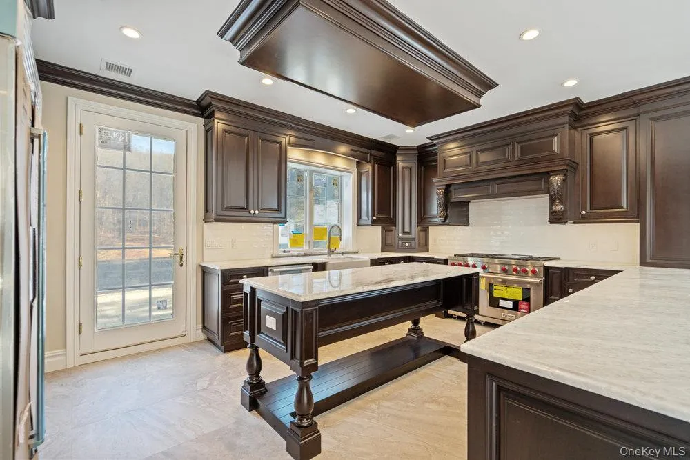 Kitchen with dark brown cabinetry, backsplash, crown molding, and recessed lighting Kitchen with dark brown cabinetry, backsplash, crown molding, and recessed lighting